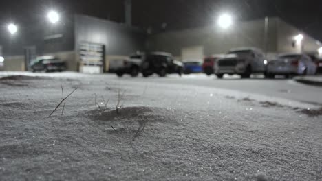 Snow-Falling-On-Ground-Near-Parking-Lot-At-Night-In-Montreal,-Canada
