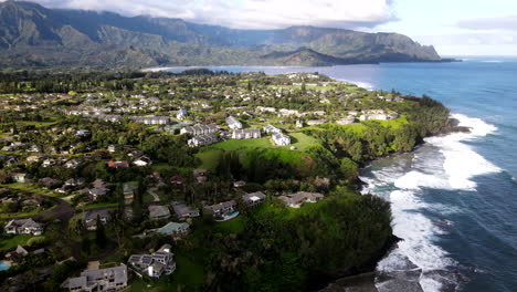 Aerial-Pass-Over-Princeville,-HI-on-Clear-Day-with-Mountains