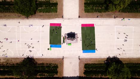 Toma-De-Arriba-Hacia-Abajo,-Canchas-Deportivas-Aéreas-Llenas-De-Escolares-En-Un-Parque.