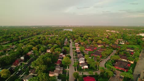 Aerial-shot-of-a-green-suburban-neighborhood-with-houses-and-trees,-captured-during-sunset,-peaceful-residential-area