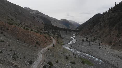 Drone-Aéreo-Sigue-A-Una-Camioneta-Conduciendo-A-Través-Del-Valle-De-La-Llanura-Alpina-Montañas-Paquistaníes