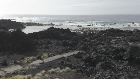 Rocky-shore-of-Mosteiros,-Sao-Miguel-with-tumultuous-sea-and-cloudy-skies,-showcasing-rugged-black-volcanic-terrain