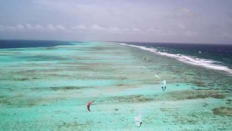 Kitesurfer-Gleiten-über-Das-Lebendige,-Klare-Blaue-Wasser-Von-Los-Roques,-Luftaufnahme