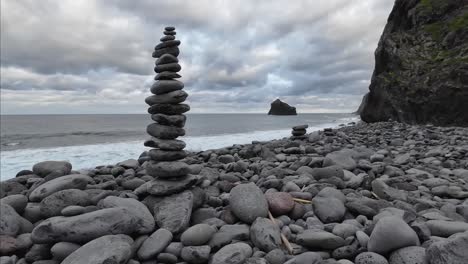 Stone-tower-on-a-stone-beach-with-the-beach-in-the-background-on-a-cloudy-day-and-the-waves-slowly-moving-in