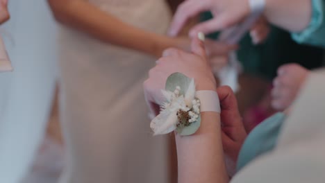 Close-up-of-a-wrist-corsage-being-adjusted-at-a-wedding
