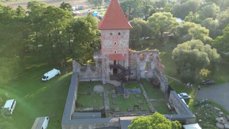 Medieval-Chudow-castle-with-a-tower,-walls,-and-courtyard-during-a-beautiful-summer-day-surrounded-by-lush-greenery,-grass,-and-trees