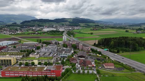 Hünenberg,-Schweiz-Mit-üppigen-Grünen-Feldern-Und-Gebäuden-Unter-Einem-Wolkigen-Himmel,-Luftaufnahme