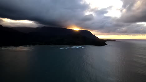 Alto-Zoom-Aéreo-Hacia-La-Puesta-De-Sol-Sobre-La-Oscura-Y-Nublada-Bahía-De-Hanalei