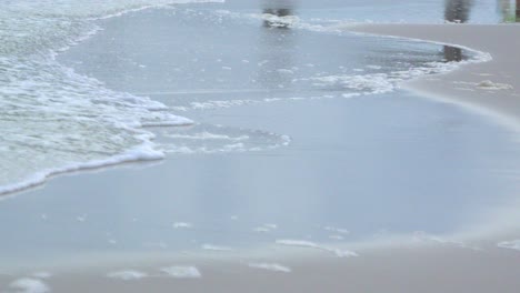 Eine-Nahaufnahme-Von-Wellen,-Die-über-Den-Sand-Spülen
