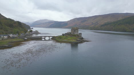 Castillo-De-Eilean-Donan-Y-Las-Tierras-Altas-Escocesas-Circundantes-En-Un-Día-Nublado,-Vista-Aérea