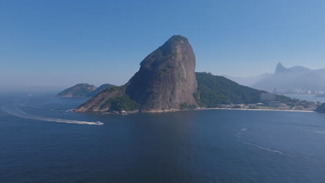 Breite-Luftaufnahmen-Des-Zuckerhuts-Mit-Einer-Bootsüberfahrt-Davor-Und-Rio-De-Janeiro-Im-Hintergrund-Während-Des-Tages