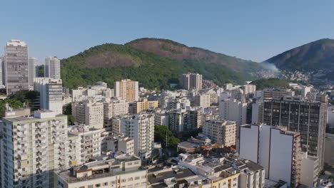 Wide-aerial-footage-flying-over-the-apartment-buildings-of-Botafogo-neighborhood-in-Rio-de-Janeiro-with-a-fire-in-a-favela-in-the-background