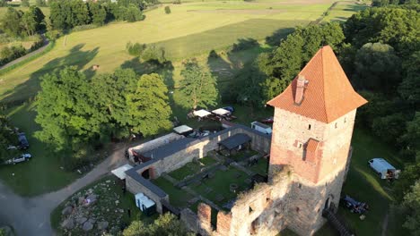 Medieval-Chudow-castle-with-a-tower,-walls,-and-courtyard-during-a-beautiful-summer-day-surrounded-by-lush-greenery,-grass,-and-trees