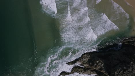 Aerial-waves-breaking-on-beach,-overhead-tracking-forwards-4K