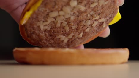 Hands-opening-a-cheese-burger-in-black-background