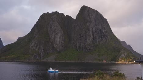 Cámara-Lenta-De-Un-Barco-De-Pescadores-Que-Pasa-Frente-A-Las-Montañas-De-Hamnøy-Cerca-De-Reine,-Islas-Lofoten,-Noruega