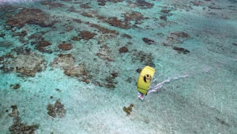Ein-Gelber-Kitesurfer-Gleitet-über-Ein-Korallenriff-In-Der-Nähe-Von-Sebastopol,-Lebendige-Unterwasserdetails-Sichtbar,-Luftaufnahme