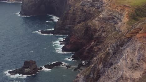 Steep-eroded-escarpment-cliffs-drop-off-into-black-sand-beach-on-North-shore-of-West-Maui