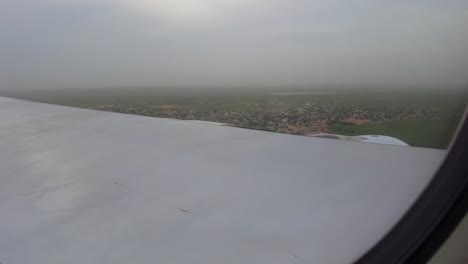 Blick-Aus-Dem-Flugzeugfenster-Auf-Ein-Flugzeug,-Das-Durch-Wunderschöne-Wolken-Fliegt-Und-Auf-Einer-Grünen-Landschaft-In-Dakar,-Senegal-Landet