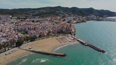 Sitges-city-and-coastline-in-spain-with-mountains-in-the-background,-aerial-view