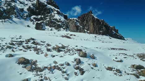 Luz-Tenue,-Cordillera-Cubierta-De-Nieve-Y-Rocas,-Panorámica-Aérea-Hacia-La-Izquierda