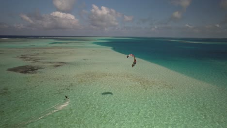 Aerial-shot-of-a-kitesurfer-gliding-over-the-clear-waters-of-Los-Roques
