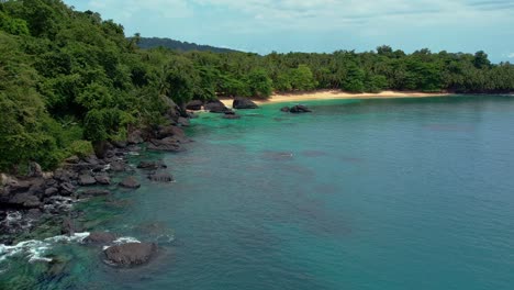Aerial-view-of-Secluded-beach-surrounded-by-lush-jungle-in-São-Tomé-e-Principe-Island