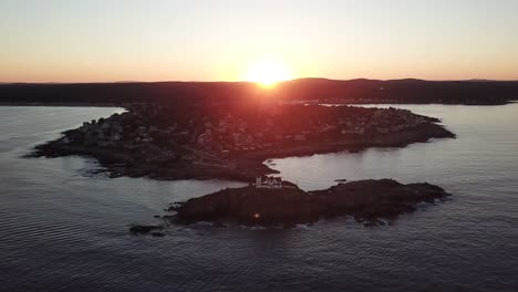 Aerial-drone-video-of-the-ocean-coastline-and-lighthouse-at-sunset-at-Nubble-Lighthouse-near-Cape-Neddick-and-York-Beach,-Maine,-United-States-of-America