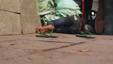 Ein-Barfüßiger,-Von-Trauer-Geplagter-Armer-Mann-Mit-Zerrissener-Und-Schäbiger-Kleidung,-Der-Schlafend-Auf-Einer-Belebten-Indischen-Marktstraße-Gefunden-Wurde