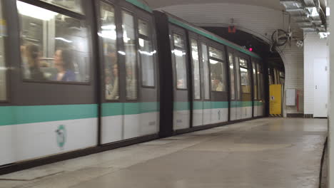 Eine-Volle-Metro-Mit-Menschen-In-Paris,-Die-Den-Bahnhof-Verlassen-Und-Im-Tunnel-Verschwinden,-Während-Eine-Person-Auf-Dem-Bahnsteig-Auf-Den-Nächsten-Zug-Wartet