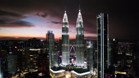 Eine-Drohne-Zieht-Aus-Der-Luft-Und-Enthüllt-Die-Skyline-Der-Stadt-Kuala-Lumpur-Und-Die-Berühmten-Kuala-Lumpur-Towers,-Umgeben-Von-Vielen-Wolkenkratzern