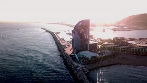 Aerial-Shot-Of-Hotel-W-Barcelona-Surrounded-By-the-Atlantic-Ocean-At-Sunset