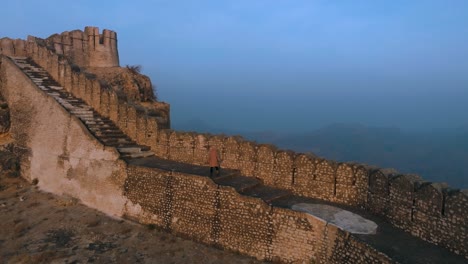 Drohnenflug-über-Der-Ranikot-Festung-In-Sindh,-Pakistan---Mann-Läuft-Auf-Historischer-Ruinenmauer