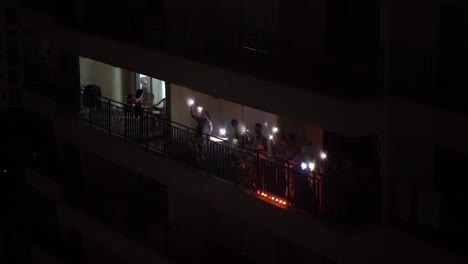 People-standing-in-their-balcony-and-waving-with-lights-in-their-hands