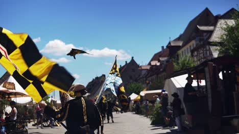 Video-showing-a-people-waving-the-flags-of-Neuburg-a-der-Donau-and-Palatinate-Neuburg-during-the-Wallenstein-Festspiele-in-Altdorf,-Bavaria
