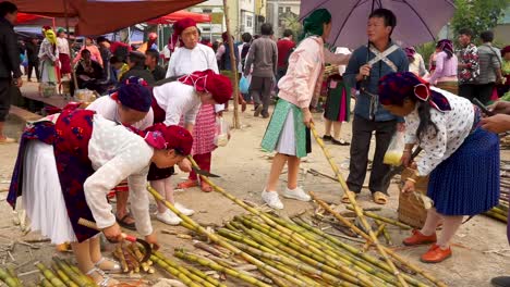 Women-in-traditional-clothes-cutting-bamboo-on-a-market-in-Dong-Van,-Vietnam