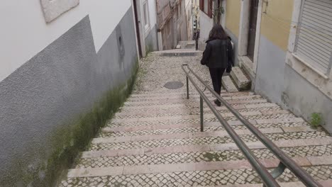 Walking-down-a-steep-set-of-stair-cases-in-Lisbon-Portugal,-following-a-person-in-black