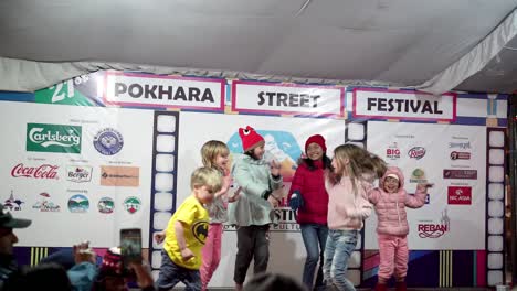 Niños-Disfrutando-Y-Divirtiéndose-Bailando-Y-Saltando-En-El-Escenario-Durante-El-21º-Festival-Callejero-En-Pokhara,-Nepal