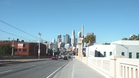 LA:-Downtown-skyline-from-1st-Street-Bridge-with-traffic-and-a-train-line---Los-Angeles-California,-USA