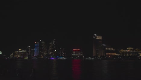 Blick-über-Den-Fluss-In-Shanghai-Bei-Nacht-Mit-Einem-Gebäude,-Das-Bewegtes-Neonlicht-Zeigt