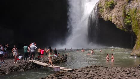 Asiatische-Frau-Genießt-Den-Berühmten-Tegenungan-Wasserfall-Auf-Bali-Mit-Menschen,-Die-Im-Hintergrund-Darauf-Baden