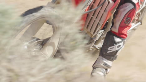 Zeitlupe:-Ein-Dirtbiker-Fährt-Mit-Seinem-Roten-Motorrad-Durch-Die-Wüste-Und-Peitscht-Um-Eine-Berme
