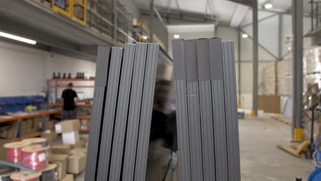 Installing-foam-separation-bumper-on-solar-panels-before-shipping-at-warehouse-with-employees,-Handheld-closeup-shot