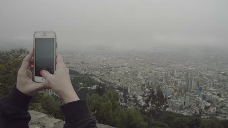 Frauenhände-Machen-Mit-Ihrem-Smartphone-Ein-Panoramabild-Der-Innenstadt-Von-Bogotá,-Kolumbien-Von-Den-Hügeln-In-Monserrate-Aus