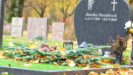 A-Beautifully-Designed-Elevated-Gravestone-With-Flowers-And-Grass-On-An-Autumn-Day-In-Kviberg-Cemetary,-Gothenburg,-Sweden---Medium-Pan-Shot
