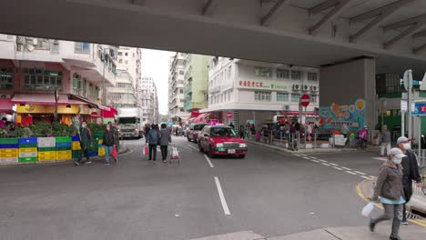 Local-Asian-population-doing-the-groceries-while-wearing-face-masks-at-the-To-kwa-wan-old-market-and-walking-over-the-gray-asphalt-road-in-Hong-Kong