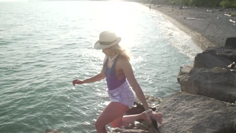 A-Sexy-Lady-Jumping-In-The-Big-Rocks-Near-The-Shallow-Sea-Water-During-Sunset-In-Ontario,-Canada---Close-Up-Shot