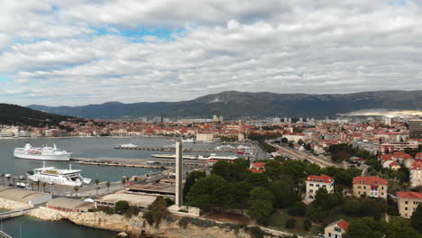 Drone-push-up-slowely-while-turning-to-reveal-the-beautiful-city-of-Split-and-the-ferry-boats-in-the-harbor-with-dramatic-clouds-in-background