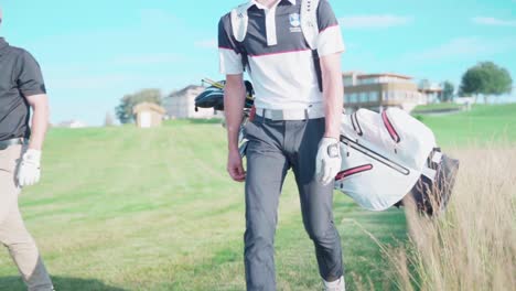 Golfer-on-golf-course-carrying-bag,-walking-from-clubhouse