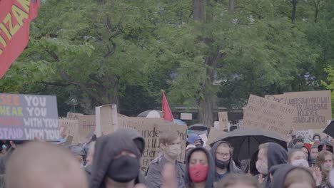 Crowd-of-protester-filmed-from-the-front-protesting-and-holding-signs-against-racism-while-cheering-and-raising-fists-at-a-black-lives-matter-protest-in-Stuttgart,-Germany